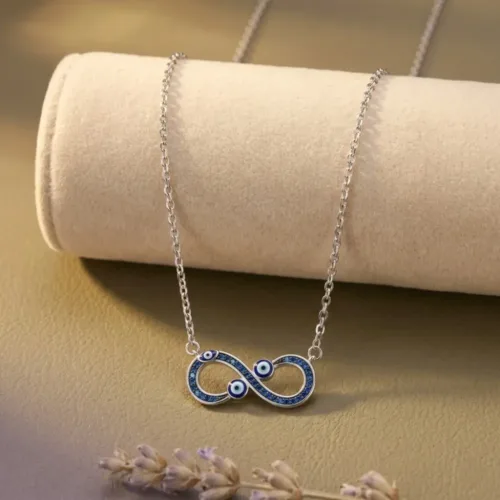 Beautifully styled infinity evil eye necklace protection jewelry resting elegantly on a beige velvet roll