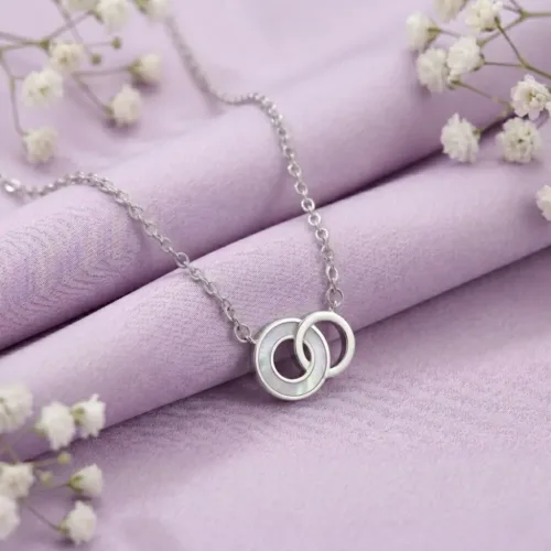 Beautiful mother of pearl daily wear jewelry resting on a soft lavender fabric with white flowers