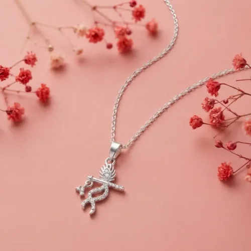 Elegant Silver Lord Krishna pendant with chain resting gracefully on a soft pink background surrounded by delicate red flowers.