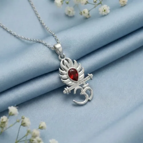 Elegant 925 Silver Om Flute Pendant resting beautifully on a soft blue silk fabric surrounded by delicate white flowers, showcasing its premium finish.
