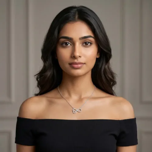 Elegant Indian woman wearing the silver infinity heart pendant with chain paired with an off-shoulder black top