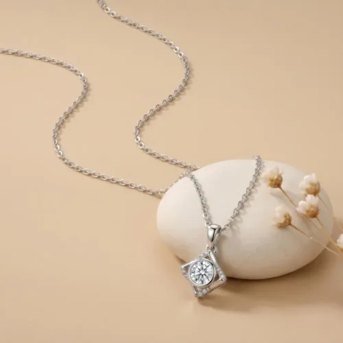 A beautifully styled sterling silver solitaire pendant daily wear resting on a smooth white pebble with delicate flowers