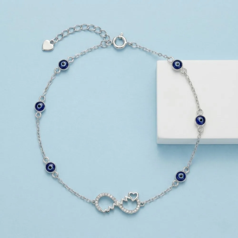 Evil Eye Silver Anklet Top view of the sparkling evil eye silver anklet featuring a CZ studded infinity heart on a soft blue background