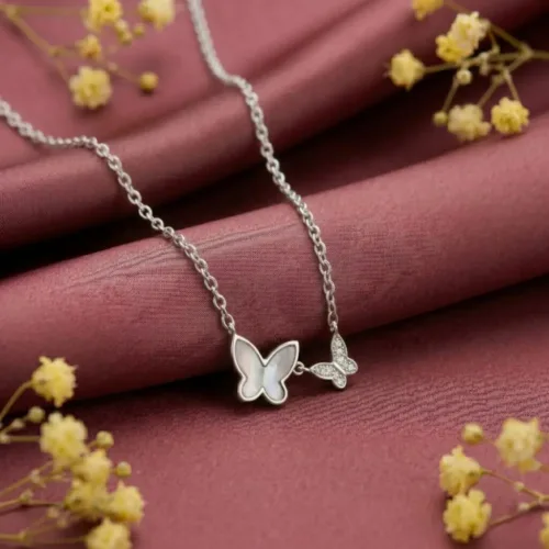 Beautiful mother of pearl butterfly necklace resting gracefully on soft maroon silk fabric with yellow flowers