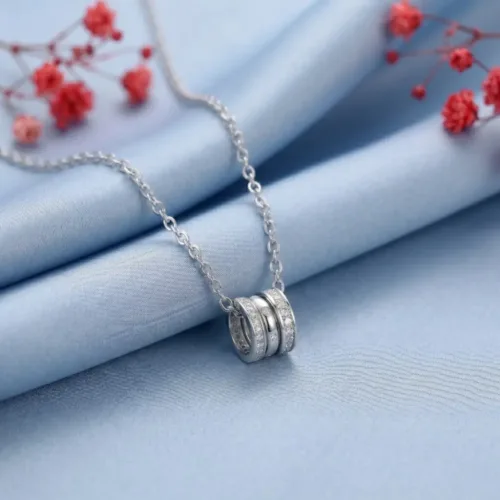 Beautiful three circle necklace for women resting on soft blue silky fabric with red floral props