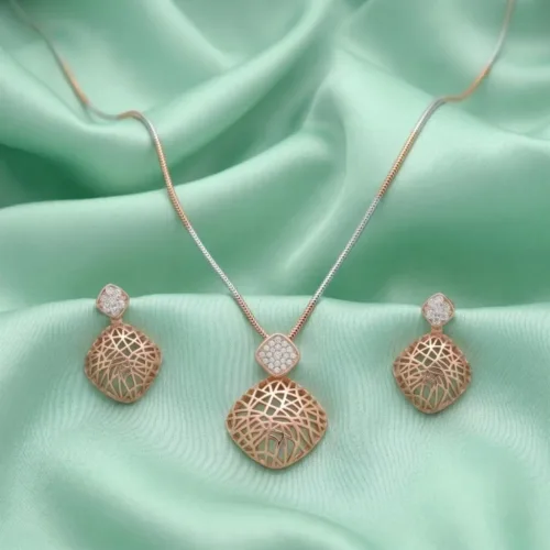 Close up view of the geometric rose gold pendant set with CZ stones resting elegantly on green silk fabric