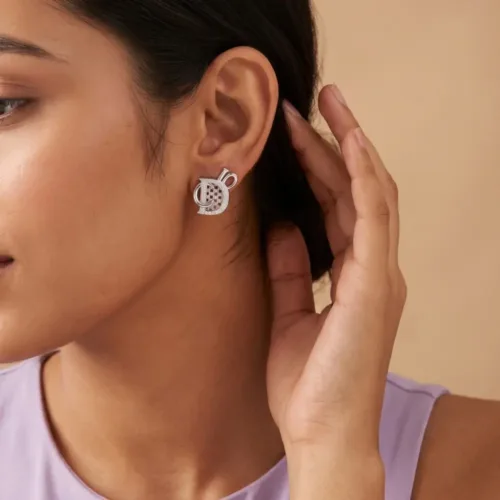 Elegant model wearing the monogram style silver studs, demonstrating the comfortable everyday fit and bold architectural look on the earlobe.