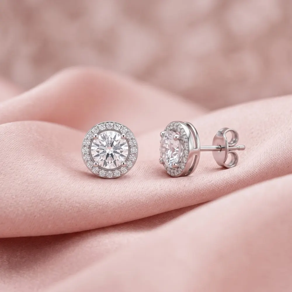 Silver Halo Stud Earrings Beautiful silver halo stud earrings resting on a soft pink silk fabric, highlighting the brilliant American diamond center stone.
