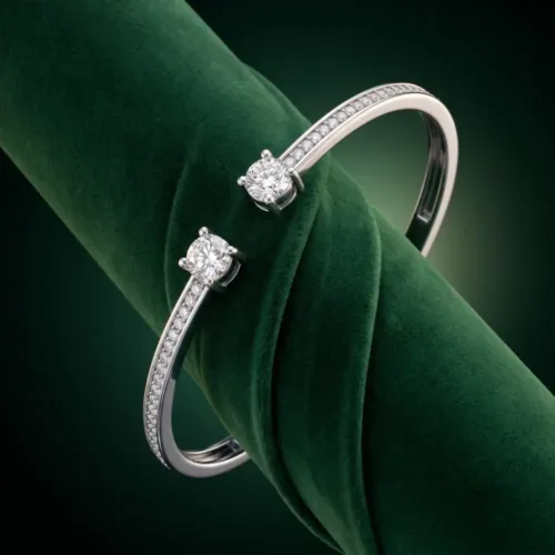 Luxurious double stone bangle bracelet silver beautifully displayed on a rich dark green velvet fabric, emphasizing the brilliant-cut cubic zircons.