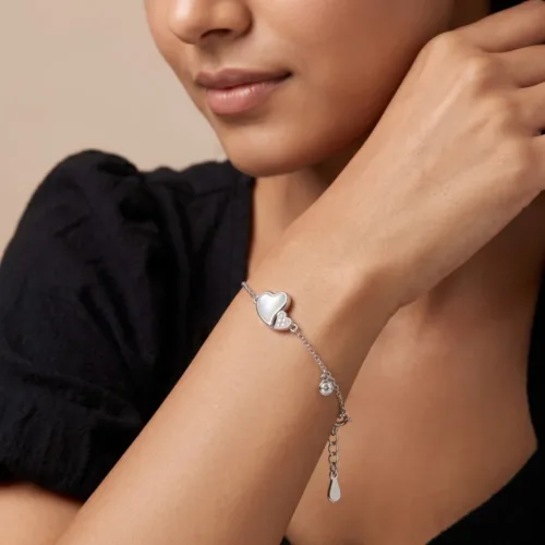 Woman wearing an elegant silver heart bracelet with cubic zirconia and mother of pearl, showcasing the adjustable fit on the wrist.