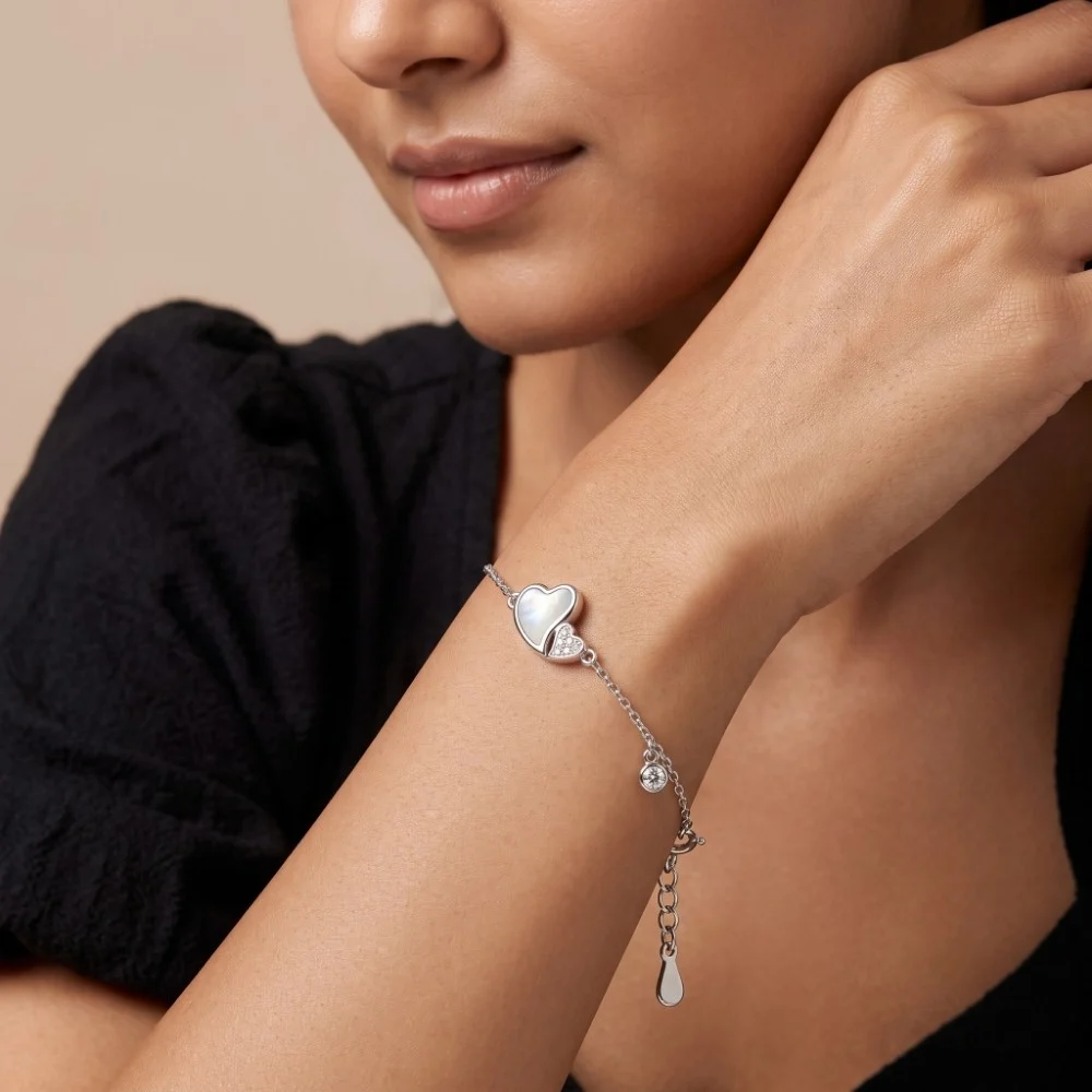 Silver Heart Bracelet with Cubic Zirconia Styled Woman wearing an elegant silver heart bracelet with cubic zirconia and mother of pearl, showcasing the adjustable fit on the wrist.