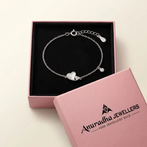 Interlocking silver heart bracelet securely placed inside a signature pink Anuradha Jewellers gift box on black velvet.