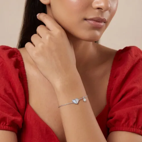Woman styling a heart shape silver bracelet on her wrist, highlighting the delicate adjustable link chain and comfortable daily fit.