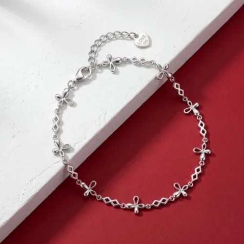 A delicate silver flower bracelet gracefully displayed on a modern red and white textured background, highlighting its stone-free design.