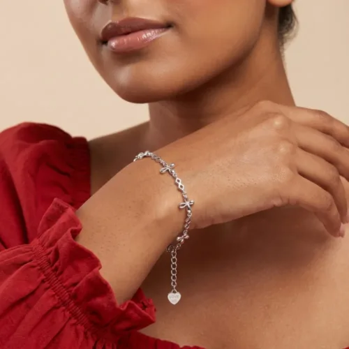 Woman styling an everyday wear silver flower bracelet on her wrist, showcasing its dainty design and the engraved LOVE 925 tag.