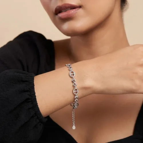 Woman wearing a delicate silver bow bracelet on her wrist, highlighting the comfortable everyday fit and elegant alternating links.