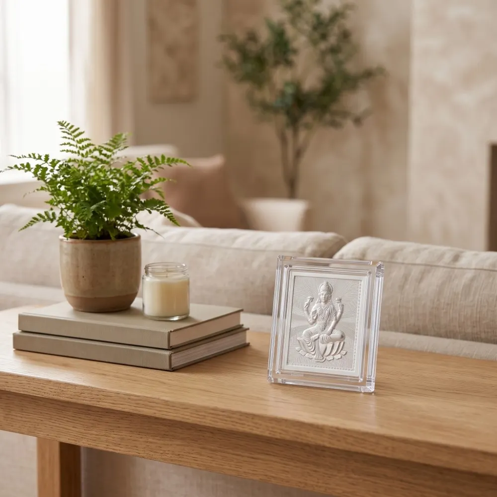 Silver Laxmi Frame for Diwali Gift – Home Display Silver Laxmi frame for Diwali gift displayed on a wooden table beside a plant and candle