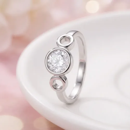 Close-up of the modern open circle silver ring resting elegantly on a white ceramic dish, showcasing the polished metallic finish and brilliant center stone.