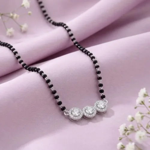 The beautiful black beads mangalsutra silver resting elegantly on soft pink fabric, highlighting its modern ad mangalsutra design and sparkling stones.
